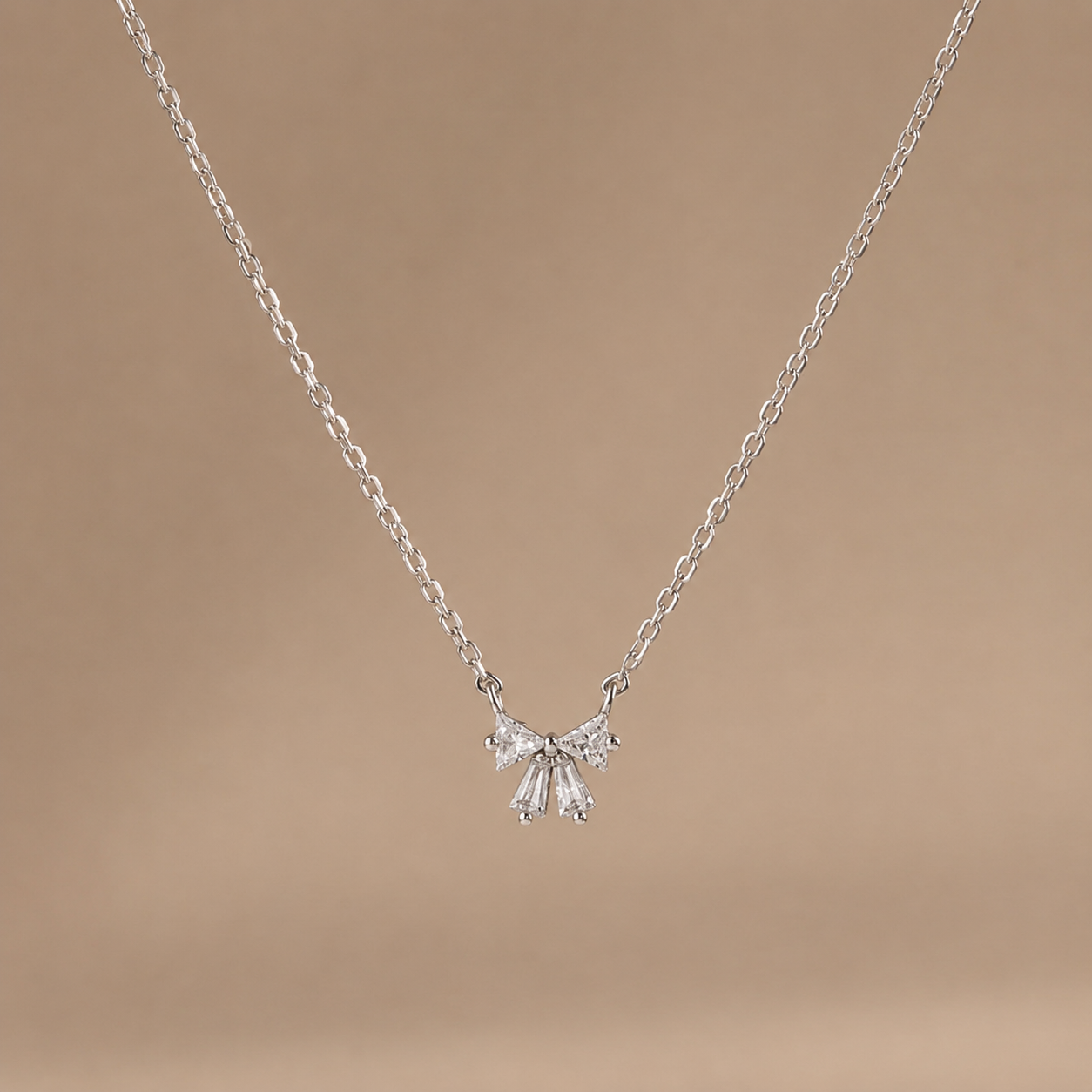 Silver necklace with a delicate pendant on a brown background